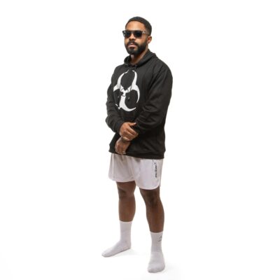 Stylish man wearing sportswear and sunglasses poses confidently in studio.