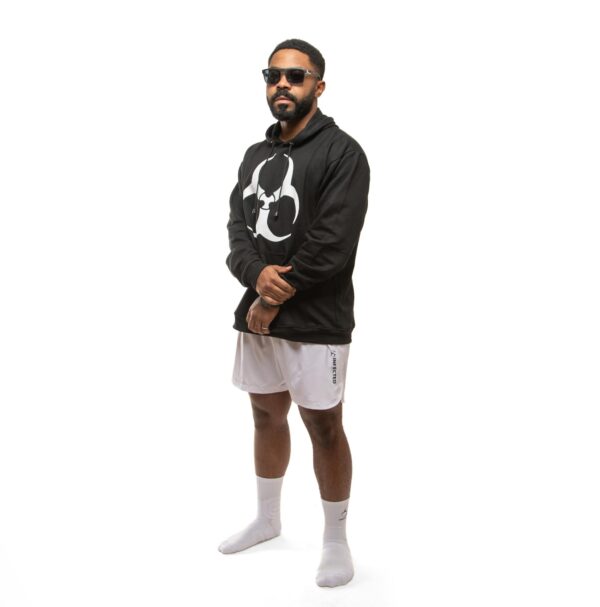 Stylish man wearing sportswear and sunglasses poses confidently in studio.